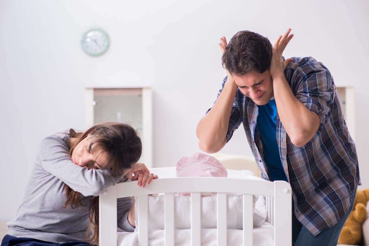Eltern vor Bett schreiendes Baby
